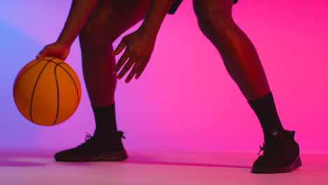 Nahaufnahme-Eines-Studioporträts-Eines-Männlichen-Basketballspielers,-Der-Den-Ball-Vor-Rosa-Beleuchtetem-Hintergrund-Dribbelt-Und-Hüpft-7